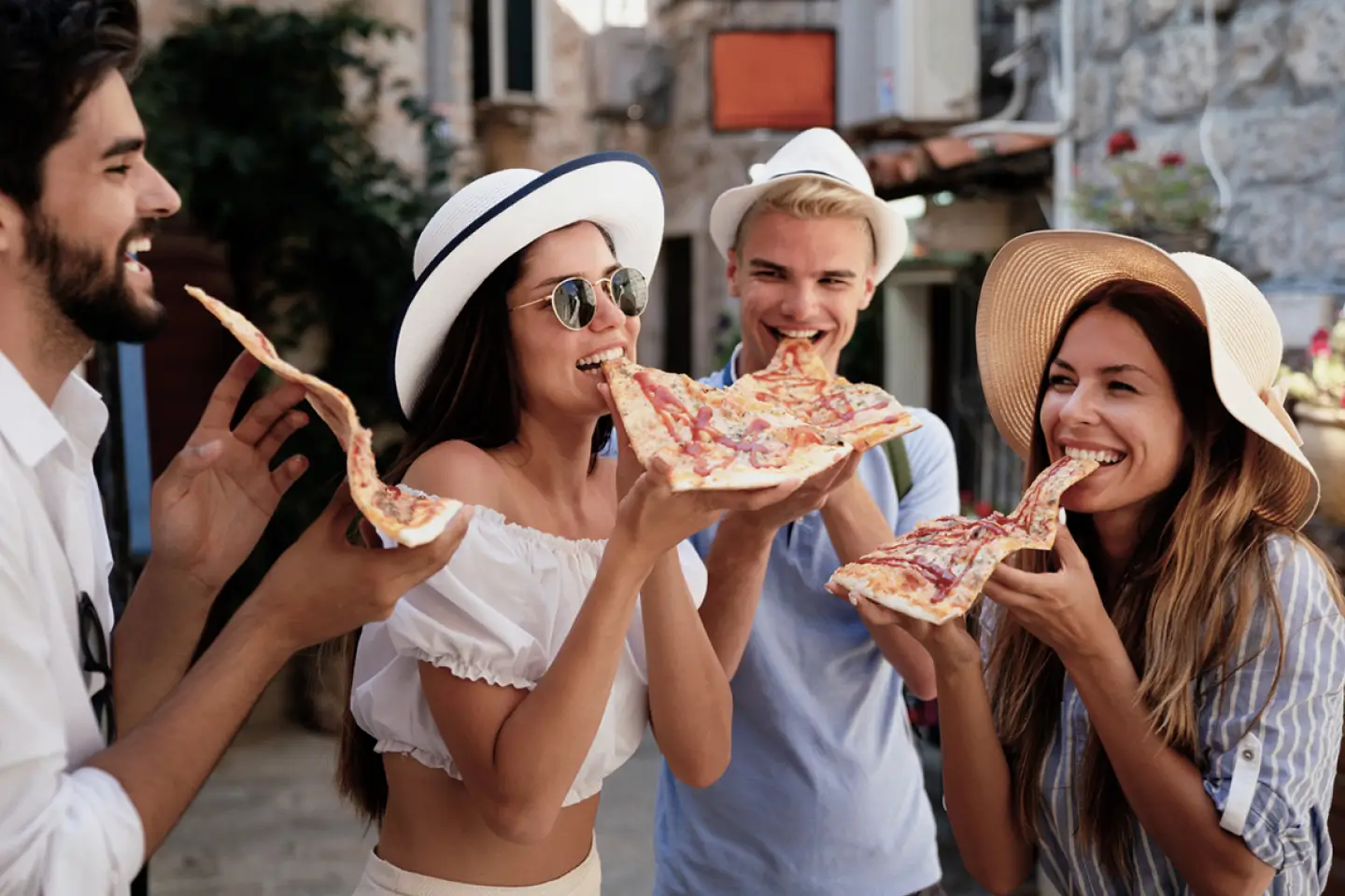four friends eating large slices of pizza together